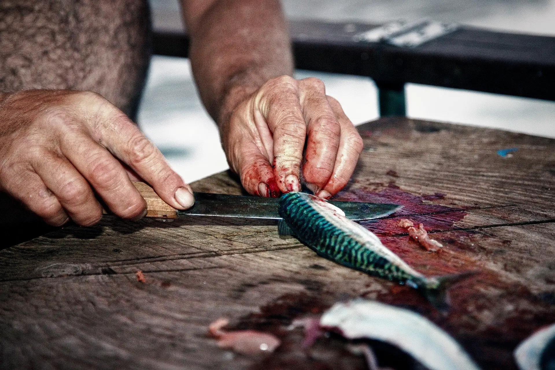 A person filleting a small fish on a table