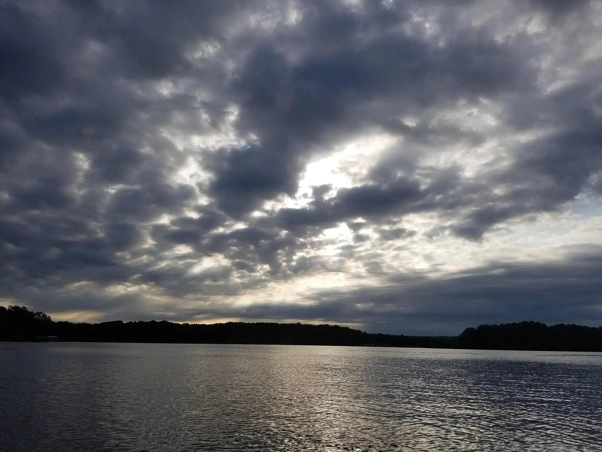 A lake covered with cloudy skies at sunset